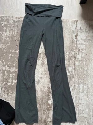 Mörkgröna yoga pants  - Säljer ett par mörkgröna leggings med bootcut-ben och bred linning i midjan. De är stretchiga och har en mjuk, bekväm passform. Perfekta för en avslappnad och trendig look.