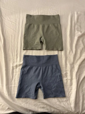 Två par seamless shorts 157, S - Två par seamless shorts från 157 i storlek S. Ena paret är gröna och det andra är blå, båda med hög midja och ribbad linning. Perfekta för träning eller chill. Mjukt och stretchigt material som sitter skönt på kroppen. Säljer båda för 50kr