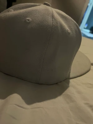 Vit New Era NY snapback keps - Säljer en vit snapback keps från New Era med svart NY Yankees-logga framtill och New Era-logga på sidan. Klassisk flat brim och broderade ventilationshål. Perfekt för dig som gillar streetwear och sportig stil. Köpte den för 500.