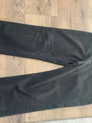 Svarta raka jeans i storlek L - Säljer ett par svarta jeans med rak passform. Jeansen är tillverkade i en mix av, polyester, viskos och polyamid vilket gör dem både bekväma och slitstarka. Perfekta för dig som gillar en clean och enkel stil.