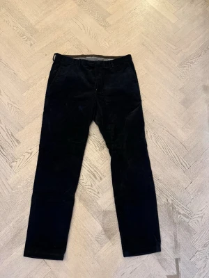 Svarta manchesterbyxor Oscar Jacobson - Snygga svarta manchesterbyxor från Oscar Jacobson. Klassisk rak passform med midwaist och diskret design. Perfekta för dig som gillar stilrena och tidlösa plagg. Materialet är mjuk manchester som ger en skön känsla och cool look.