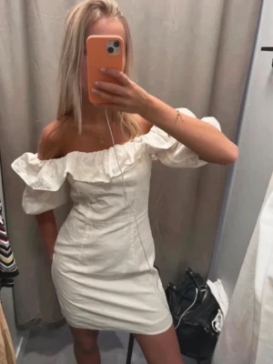 Vit offshoulder klänning💓💓 - Trendig vit kortklänning med offshoulder och volangdetalj längs urringningen. Klänningen har en figurnära passform och puffiga ärmar som ger en romantisk vibe. Perfekt för sommarens alla tillfällen.💓helt oanvänd så den har inga defekter💓