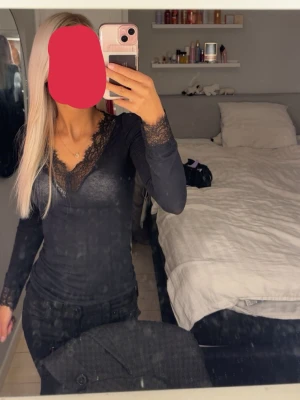Svart långärmad intimissimi tröja med spets - Säljer en svart långärmad topp med v-ringning och fina spetsdetaljer vid halsringningen och ärmsluten. Toppen har en slim passform och är tillverkad i ett mjukt material som sitter snyggt på kroppen. Perfekt att styla med jeans eller kjol.