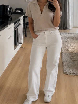 Beige kortärmad polotopp från socl - Snygg beige polotopp från socl med korta ärmar och öppen krage. Tillverkad i mjuk bomullsmix som känns skön mot huden. Perfekt till jeans eller kjol för en avslappnad look.