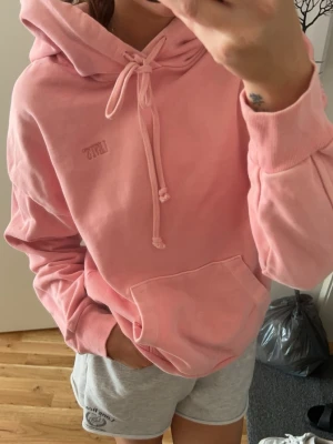 Rosa hoodie från Levi's med huva - Säljer en ljusrosa hoodie från Levi's med broderad logga på bröstet. Hoodien har stor ficka framtill, justerbar dragsko i huvan och ribbade muddar vid ärmar och nederkant. Tillverkad i mjuk bomullsblandning, perfekt för en avslappnad stil.