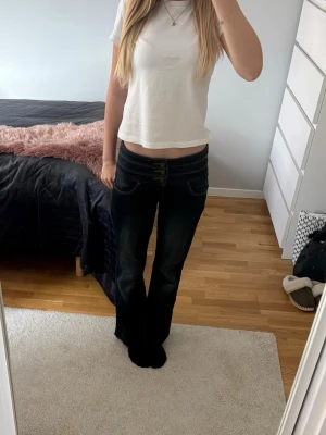 Mörkblå bootcut jeans  - Säljer ett par mörkblå mid/low rise bootcut jeans med tre knappar. Jeansen är i väldigt bra skick då de inte använts mycket. Perfekta till en basic outfit men går såklart också att styla upp. Jeansen är i bra längd för mig som är 160cm. 