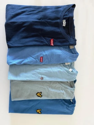 5-pack blå t-shirts från Levi's & Lyle & Scott - Säljer ett 5-pack t-shirts i olika blå nyanser från Levi's och Lyle & Scott. Alla har rund hals och korta ärmar. Två är Levi's, två är Lyle & Scott och en är gant🔥storlek: XS✅ (den mörk blåa Levis är 176 men är precis lika stor som en XS)