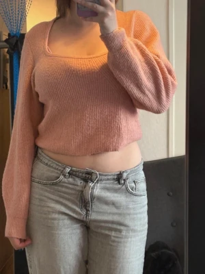 Ljusrosa stickad tröja från H&M - Mysig ljusrosa stickad tröja från H&M med croppad passform och långa ärmar. Tröjan har ribbstickad struktur och är perfekt för att skapa en söt och avslappnad look🩷