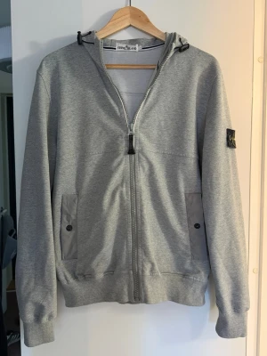 Stone island cardigan  - Grå stone island cardigan med luva med skärm på 🌟 Det är ett litet slitage längst ner på tröjan (se bild 4) men går att laga. Slitaget är inget man tänker på enligt mig! 