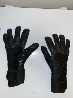 Svarta målvaktshandskar från Select - Säljer ett par svarta målvaktshandskar från Select med coola detaljer och förstärkta partier på fingrar och handflata. Handskarna har kardborreband vid handleden för extra bra passform och är tillverkade i syntetmaterial. Perfekta för dig som älskar fotboll.