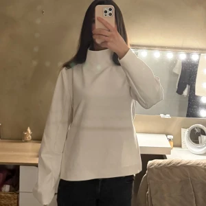 Vit polotröja med hög krage - Säljer en stilren vit polotröja med hög krage och långa ärmar. Den är gjord i ett luftigt material som funkar bra för både träning och till vardags. Säljer då den inte kommer till andvänding.