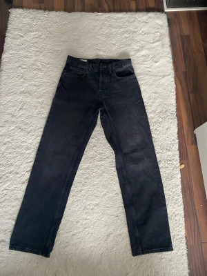 Svarta raka jeans från Zara - Säljer ett par svarta raka jeans från Zara i storlek 38. Jeansen har klassisk femficksdesign och är tillverkade i ett slitstarkt denimtyg. Perfekta för en clean och stilren look.