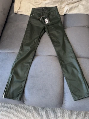 Mörkgröna jeans från stockh LM - Snygga mörkgröna jeans från stockh LM med raka ben och dragkedjor vid bensluten. Klassisk femficksmodell med bälteshällor och knappgylf. Materialet ser ut att vara bomull med lite stretch för extra komfort. Köpt för 600. Pris lapp på. Kontakta över funderingar 