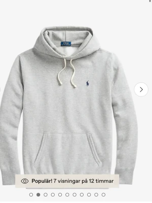 Grå hoodie från Polo Ralph Lauren - Snygg ljusgrå hoodie från Polo Ralph Lauren med klassisk huva och vita dragsnören. Har en broderad marinblå logga på bröstet och en stor magficka. Tillverkad i mjukt bomullsmaterial som är riktigt skönt mot huden. Perfekt för en avslappnad och stilren look. Pris kan diskuteras.