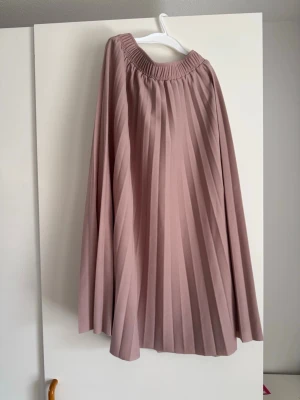 Rosa midi kjol, storlek S - En plisserad kjol i en fin rosa nyans. Kjolen har en elastisk midja för bekväm passform och faller elegant. Den veckade designen ger kjolen volym och rörelse.  Buy shipping label or pick it up from Farsta Centrum in Stockholm.