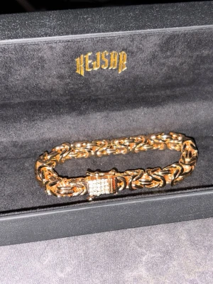 Guldfärgat armband från Kejsar - Snyggt guldfärgat armband från Kejsar med kraftig kedjelänk och ett lås dekorerat med glittrande stenar. Armbandet är 19.5cm lång och är 8mm bredd har en exklusiv känsla och passar perfekt för dig som vill sticka ut med din stil. Köpt för 1499kr men priset kan disskuteras vid snabba köp 