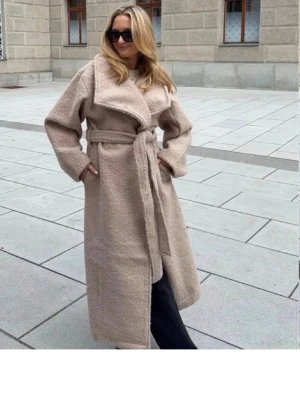 Beige teddy kappa med knytskärp - Säljer en beige teddy kappa med breda slag och knytskärp i midjan. Kappan är lång, har en oversized passform och är gjord i ett mjukt, fluffigt material som ger en trendig look. Perfekt för att hålla sig varm under kalla dagar.