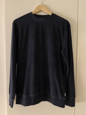 Mörkblå sweatshirt från Lindbergh - En stilren mörkblå sweatshirt från Lindbergh i relaxed fit. Tröjan har rund halsringning, långa ärmar och ribbade muddar vid ärmslut och nederkant. Perfekt för en avslappnad och trendig look.