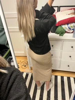 Beige omlottkjol i ribbad manchester - Snygg beige långkjol i ribbad manchester med omlott-design och slits framtill. Kjolen har en figurnära passform och är perfekt för dig som gillar en stilren och trendig look.