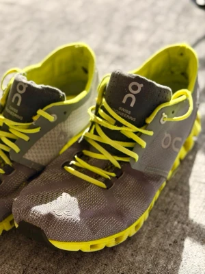 Vårens hetaste löpskor från ON Running - Säljer ett par sneakers från On i grått med neongula detaljer och sula. Skorna har ventilerande meshmaterial, gula snören och märkets logga på sidan. Lätta och sportiga med unik sula för extra komfort.