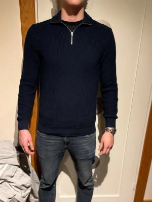 MÖRKBLÅ HALFZIP FRÅN ZARA - Snygg mörkblå stickad tröja med halv dragkedja i halsen och ribbade muddar. Tröjan har en klassisk passform och är perfekt för lager-på-lager. Materialet är mjukt och ger en stilren look.                 (Modellen är 190cm, 88kg)