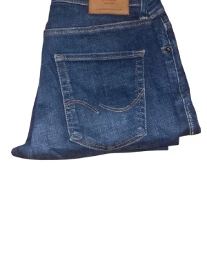 Blå jeans från Jack & Jones - Säljer ett par klassiska blå jeans från Jack & Jones med fem fickor och snygga kontrastsömmar. Jeansen har en rak passform och är tillverkade i slitstarkt denim-material. Perfekta för dig som gillar en tidlös och enkel stil.