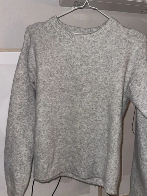 Grå stickad tröja från Kappahl - Mysig grå stickad tröja från Kappahl med rund halsringning och långa ärmar. Perfekt för kyliga dagar och enkel att matcha med olika outfits. Klassisk modell med ribbade muddar vid ärmslut och nederkant. Skriv om ni undrar något ❤️