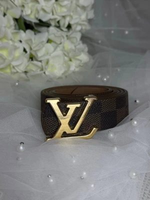  dammönstrat bälte - . Perfekt accessoar för att lyfta vilken outfit som helst. Tillverkat i canvas med läderdetaljer.