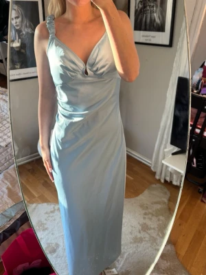 Adoore, Ljusblå långklänning med v-ringning - Finaste ljusblå långklänningen,  med v-ringning och liten cut-out framtill. Klänningen har breda axelband och figurnära passform som framhäver siluetten. Perfekt till bal och sommaren!