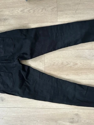 Svart nudie jeans W28 L30 - Säljer ett par svarta jeans från nudie med en smallare passform men finns fortfarande rum för benen att andas. Jeansen har normal midja och är tillverkade i ett stretchigt material för extra komfort. Perfekta till en avslappnad streetstyle-look. Storlek W28 L30