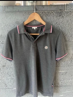  Moncler polo - Snygg grå pikétröja från Moncler storlek m bra skick.
