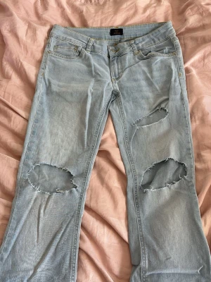 bootcut jeans med hål - Säljer dessa jätte söta ljusblå bootcut jeans med hål ifrån Nelly i storlek 36 (S)!💓 Byxorna är i ett strechigarw material och är i fint skick! Perfekt inför våren och tidig sommar! Packas och postas säkert!📦💓