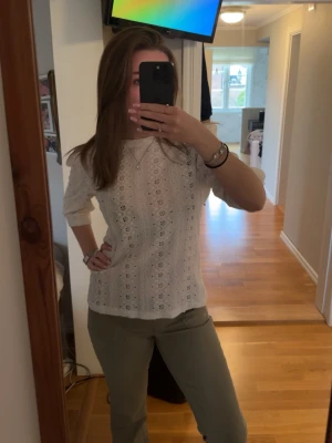 Vit spetsblus med trekvartsärm - Söt vit blus med trekvartsärm och broderade spetsdetaljer. Blusen har rund halsringning och ett luftigt, feminint mönster som ger en romantisk vibe. Perfekt att styla med jeans eller kjol för en fräsch look.