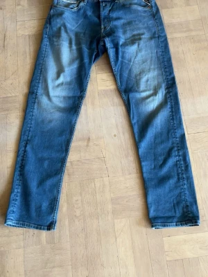 Blå  jeans från Replay - Snygga blå  jeans från Replay med klassisk femficksdesign och lätt slitna detaljer framtill och baktill. Jeansen har normal midja och raka ben. Perfekta för dig som gillar en avslappnad men trendig stil.