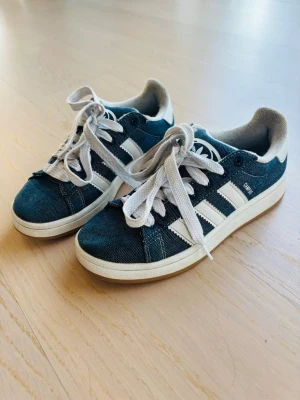Adidas Campus 00s sneakers - Ja säljer ett par jättesnygga Adidas Campus 00s sneakers i mörkblå denim med klassiska vita ränder och vit sula. De passar perfekt för sommaren för en snygg och avslappnad look. Storlek 37 1/3
