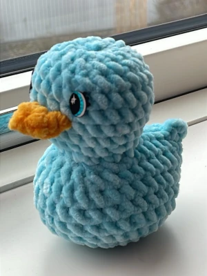 Virkad blå anka i mjukt garn - Söt handvirkad anka i ljusblått, fluffigt sammetsgarn med orange näbb och filtögon. Perfekt som studentpresent eller gosedjur. Unik och charmig detalj till rummet.