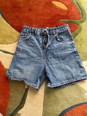 Blåa högmidjade jeansshorts - Blåa jeansshorts med hög midja från Zara. Några små synliga slitna punkter framtill, går att se på första bilden, annars i bra skick 