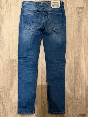 Replay Anbass Blå Jeans W30/L32 Slim Fit - Replay Anbass blå jeans i clean tvätt, slim fit modell som sitter bra och funkar till allt, storlek W30/L32, midja 39,5 cm, ytterbenslängd 104 cm, benöppning 16 cm, modellen är 185cm & väger 65kg, i fint skick.