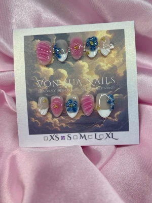 Petals (S);Short Almond - Unika handgjorda press-on naglar i rosa, blått och vitt med 3D-blommor, swirl-mönster och gulddetaljer. Korta almond och glansiga, perfekt för dig som vill ha en unik och färgglad look. 