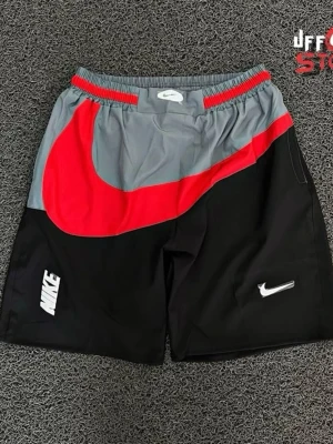 Nike färgblockade shorts med logga - Snygga shorts från Nike med färgblock i svart, grått och rött. Stora Nike-loggor på både vänster och höger ben. Elastisk midja med röd och grå detalj. Perfekta för sport eller chill.