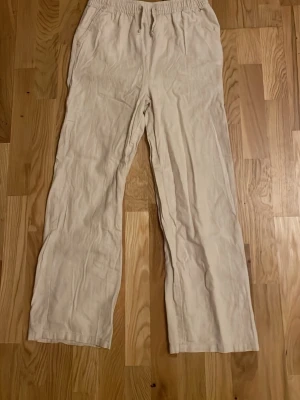 Beiga linnebyxor från Wai Wai - Säljer ett par beiga linnebyxor från Wai Wai, i storlek 146/152 med rak passform och resår i midjan. Byxorna har en avslappnad look och är tillverkade i ett lätt och luftigt linnematerial, perfekta för varma sommardagar. Mycket sparsamt använda någon enstaka gång så bör ej finnas några större skavanker☺️ Säljer då dem är för små. Dem är lite ljusare i verkligheten. Skickar helst med PostNord!