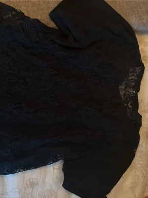 Svart spetsblus från Only - Säljer en svart blus från Only i storlek S. Blusen har korta ärmar och är tillverkad i ett genombrutet spetsmaterial med blommönster. Perfekt för dig som gillar en elegant och trendig look. Rund halsringning och mjukt tyg.