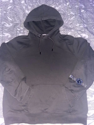 Mörkgrå hoodie från John Henric - Snygg mörkgrå hoodie från John Henric med klassisk huva och dragsnören. Hoodien har en stor magficka och är tillverkad i mjukt bomullsmaterial. Perfekt för en avslappnad och stilren look.