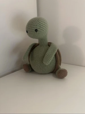 Virkad sköldpadda  - Virkad sköldpadda i grönt och brunt akrylgarn. Den har extra vikt i kroppen så den sitter stadigt. Den väger ungefär 730 g och är ca 27 cm hög. Den har säkerhetsögon som inte rekommenderas för barn under 3 år!🐢