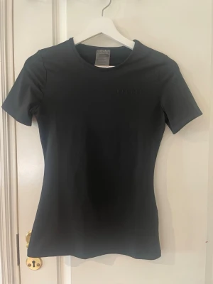 Svart t-shirt från Relode - Snygg svart t-shirt från Relode med diskret logga på bröstet. T-shirten har rund halsringning och korta ärmar. Tillverkad i mjukt och stretchigt material som sitter tight mot kroppen, perfekt för gymmet! Storlek s, använd 2 gånger endast