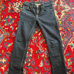 Nudie Jeans Raw - Säljer ett par sjukt  snygga mörkblå jeans från Nudie i storlek 26/32 och modell Tube Kelly som är en unisex modell! Mått: Midja - 36,5 cm, innersöm -    76,5 cm, yttersöm - 101 cm. (Notera att måtten är ungefärliga och inte exakta)