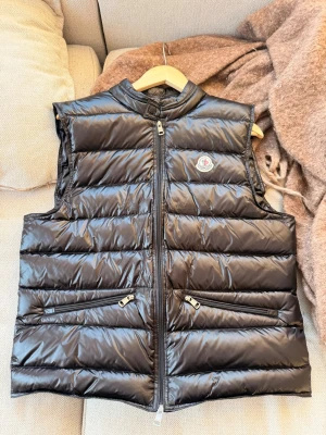 Moncler gui väst - Storlek: 4 (passar M o L) västen är i mycket bra skick. Dragkedjan är trög så därav priset 