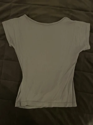 Grå croppad topp med öppen rygg - Snygg grå croppad topp med korta ärmar och öppen rygg. Perfekt för dig som gillar minimalistisk stil och vill ha något enkelt men ändå trendigt. Tunn och mjuk i materialet, passar till många olika outfits.