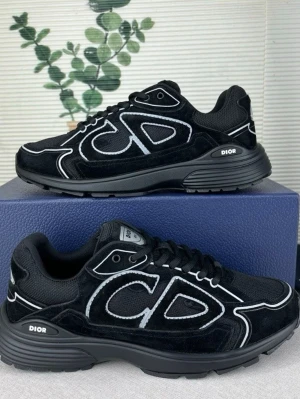 Svarta Dior sneakers med vit detalj - Snygga svarta sneakers från Dior med vita kontrastsömmar och stora CD-detaljer på sidan. Skorna har en chunky sula, mesh och mocka i ovandelen samt klassisk snörning. Perfekta för dig som vill ha en exklusiv och trendig look.