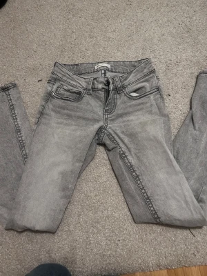 Bootcut jeans! - Säljer ett par grå jeans från Gina Tricot Jeansen har fem fickor, smala ben och snygga detaljer med knappar på bakfickorna. Klassisk passform med bälteshällor och dragkedja. Säljer då de är försmå😅🫶